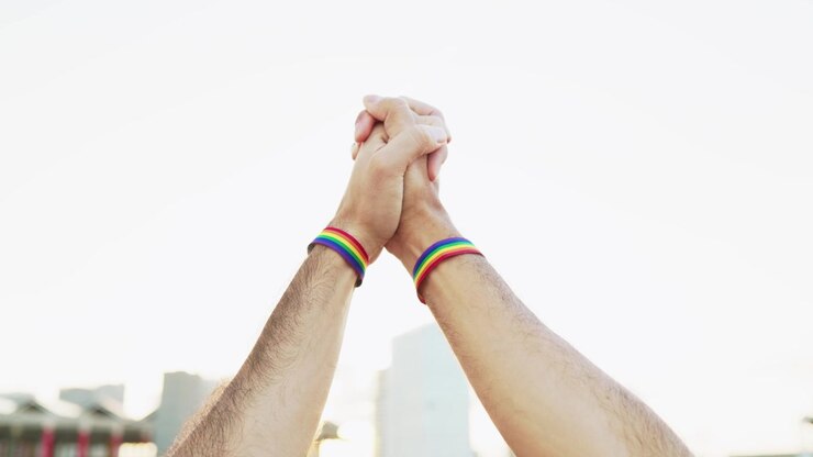 Mani giunte con braccialetti del Pride LGBTQ+.