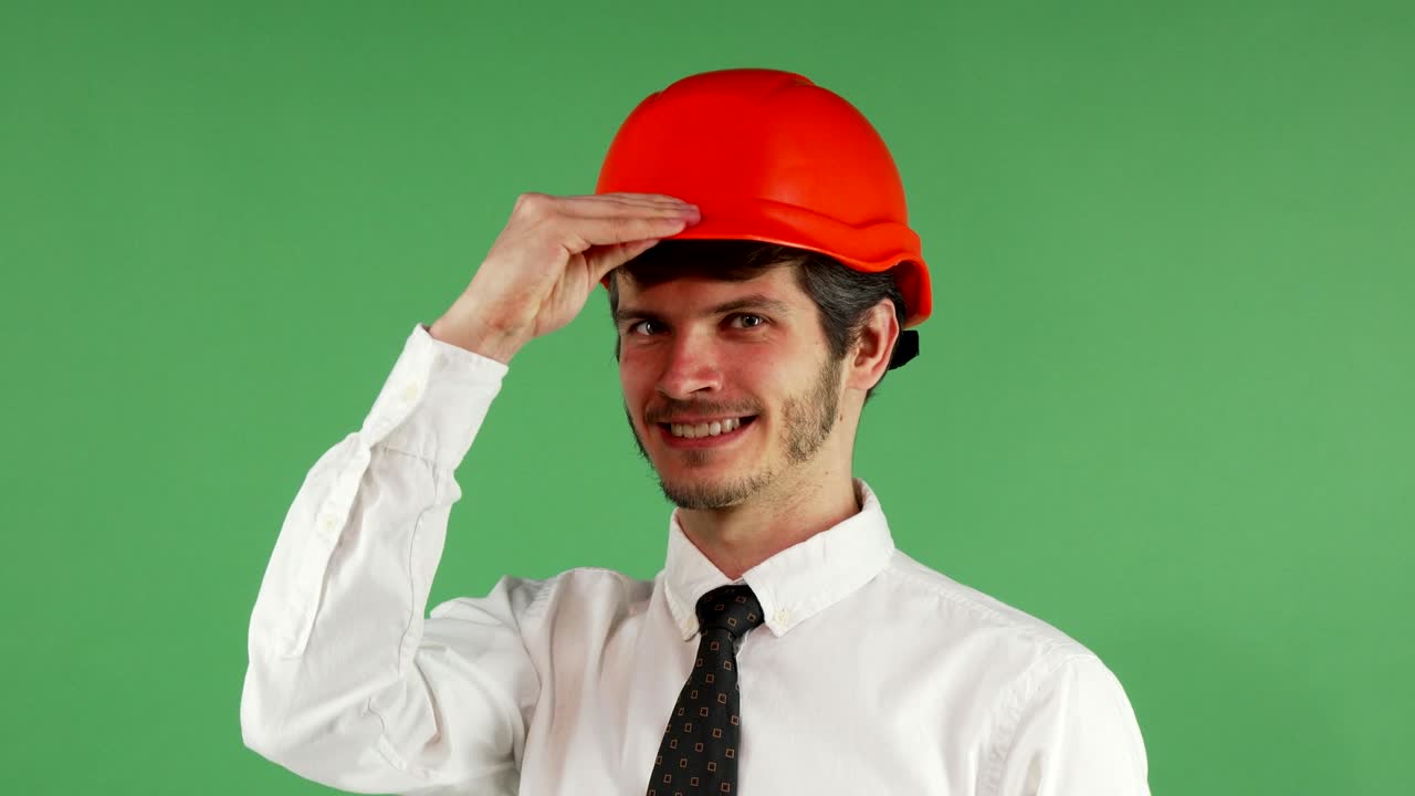 Cheerful male engineer smiling putting on his hardhat
