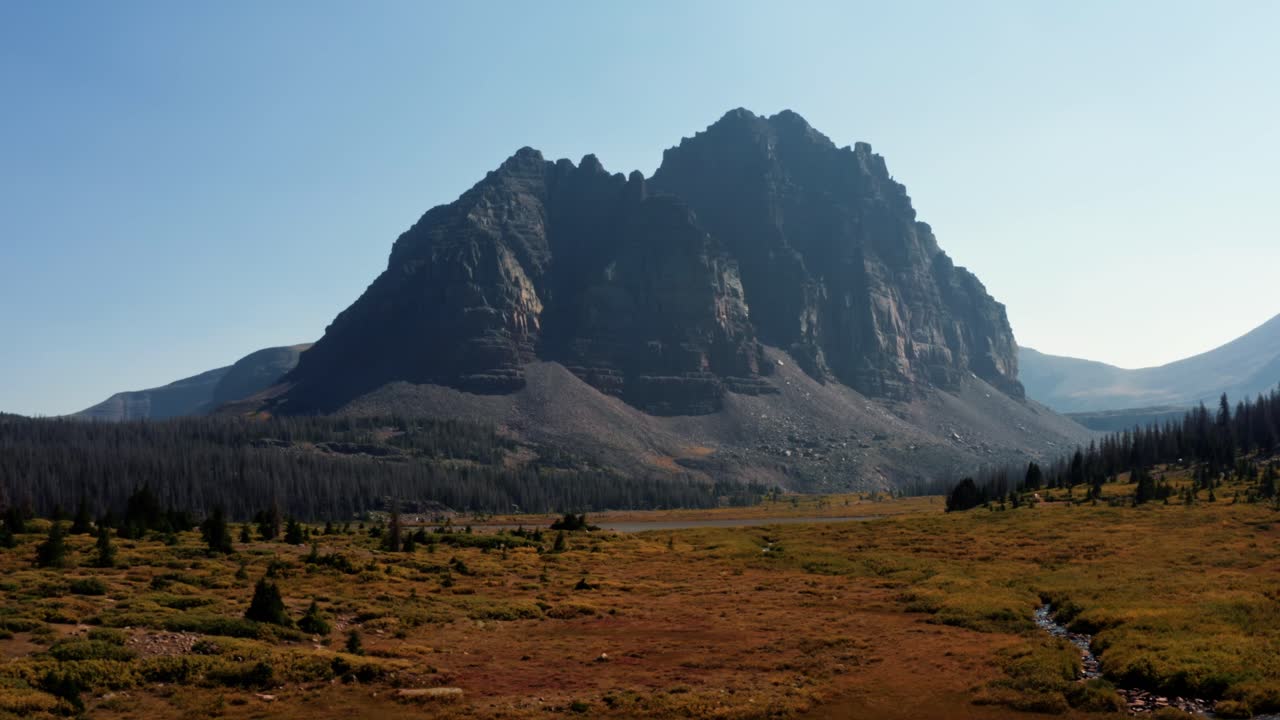 impresionante paisaje aéreo de drones, naturaleza, camiones, tiro derecho de un gran prado con un pequeño arroyo con el hermoso lago del castillo rojo inferior y pico detrás en el bosque nacional de uinta alto en utah