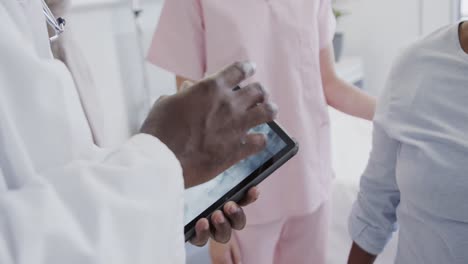 diverse male doctor with tablet and female physio treating senior female patient, slow motion