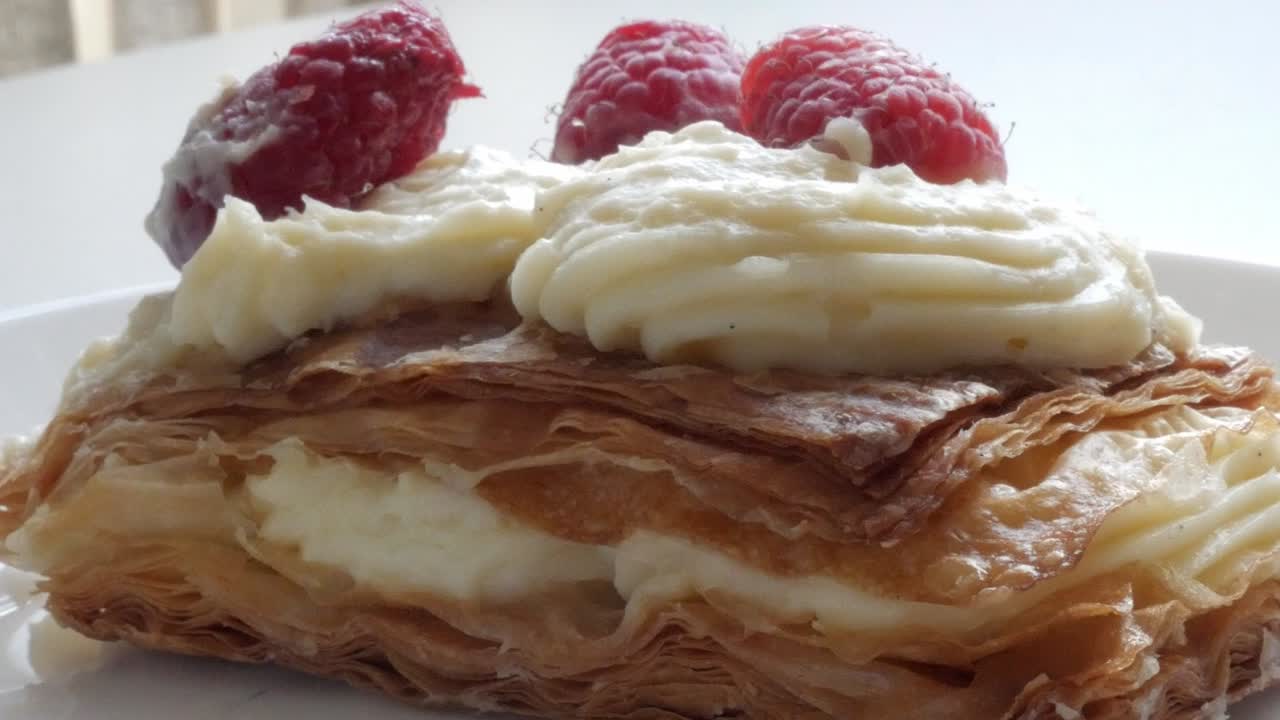 Flaky millefeuille dessert with custard cream and fresh raspberries on top