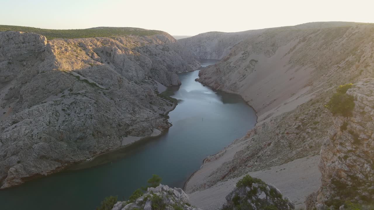 협곡의 조이스틱으로 드론을 조종하는 절벽에 앉아 있는 빨간 코트를 입은 남자