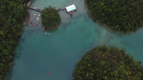 Aerial,-pontoon-style-lodge-of-Sugba-Lagoon-on-siargao-Island-floating-amid-maze-of-turquoise-water-surrounded-by-small-lush-islets-wrapped-in-a-layer-of-tropical-rainforest,-Philippines