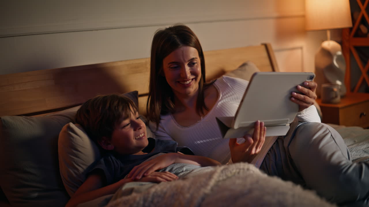 Woman son preparing sleep watching bedtime story tablet together closeup