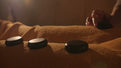 masseur putting hot stones on the body