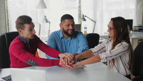 Smiling-employees-putting-hands-together.