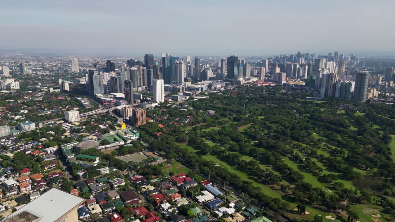 Stunning aerial flyover shot of lush Wack-wack Greenhills country club with buildings and cityscape background - Mandaluyong, Philippines