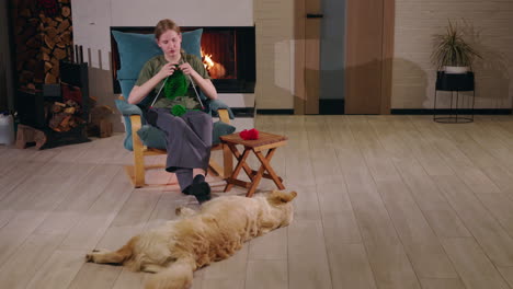 woman knitting by the fireplace with a dog