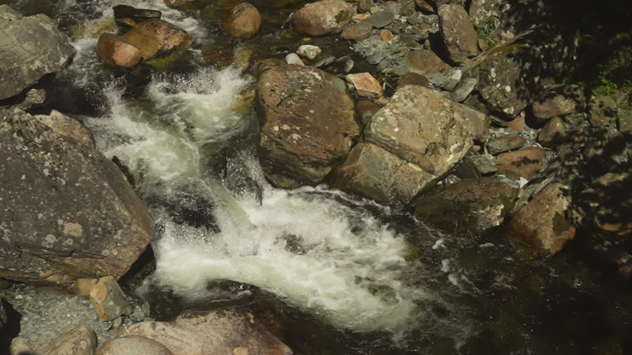 Rocky river rapids featuring whitewater at sunny highland slow motion. Steep cascade on fast mountain stream in wilderness. Clear creek flowing
