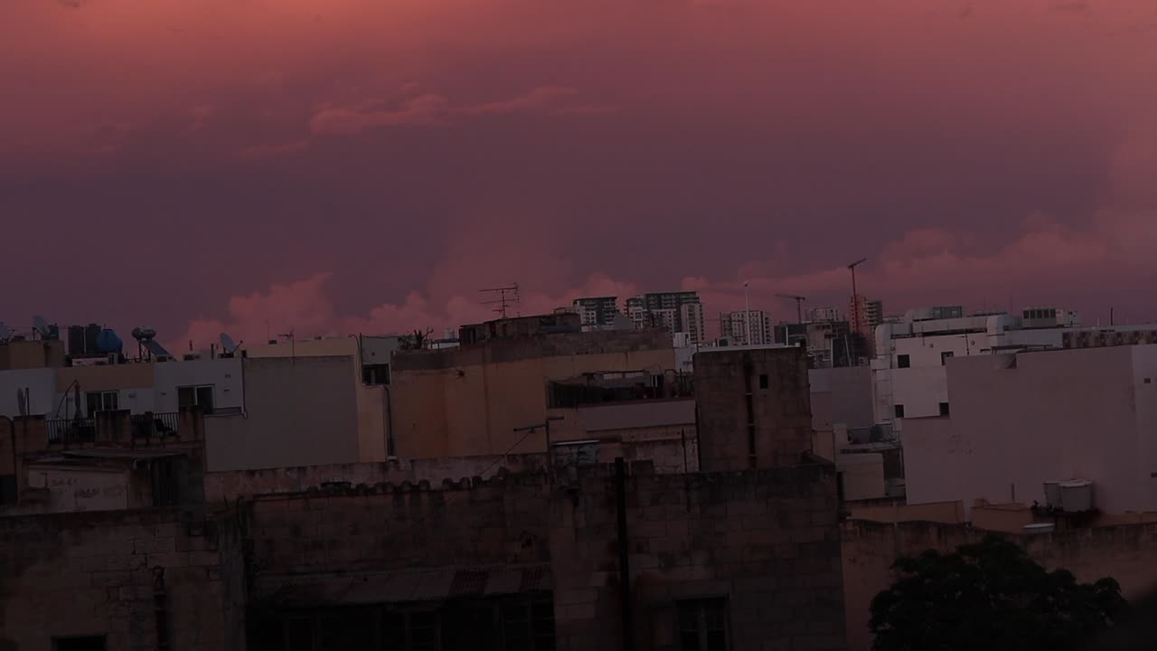 Tramonto con cielo rosso su una città mediterranea.