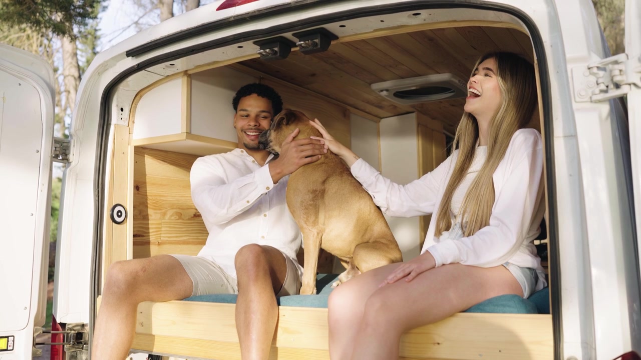 Coppia felice che accarezza il proprio cane boxer in un camper