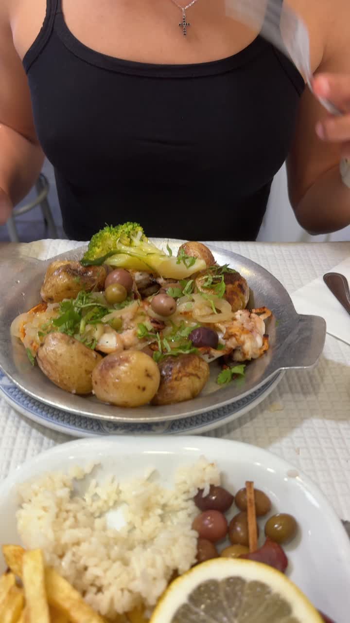A person enjoying a seafood and potato dish with various sides at a restaurant