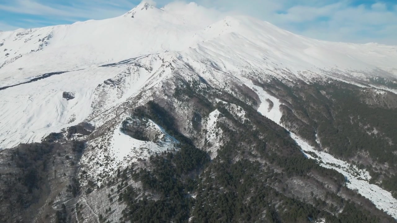 Rivelazione aerea con drone della cima innevata del Monte Etna con terreno vulcanico scuro, 4K
