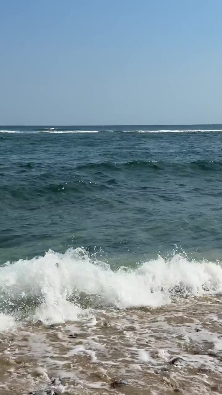 Onde del mare che si infrangono dolcemente su una spiaggia sabbiosa sotto un cielo azzurro e limpido