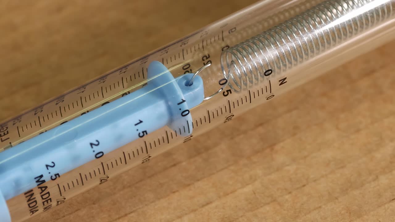 Close-up of a spring scale on cardboard, highlighting the scale markings and spring mechanism.