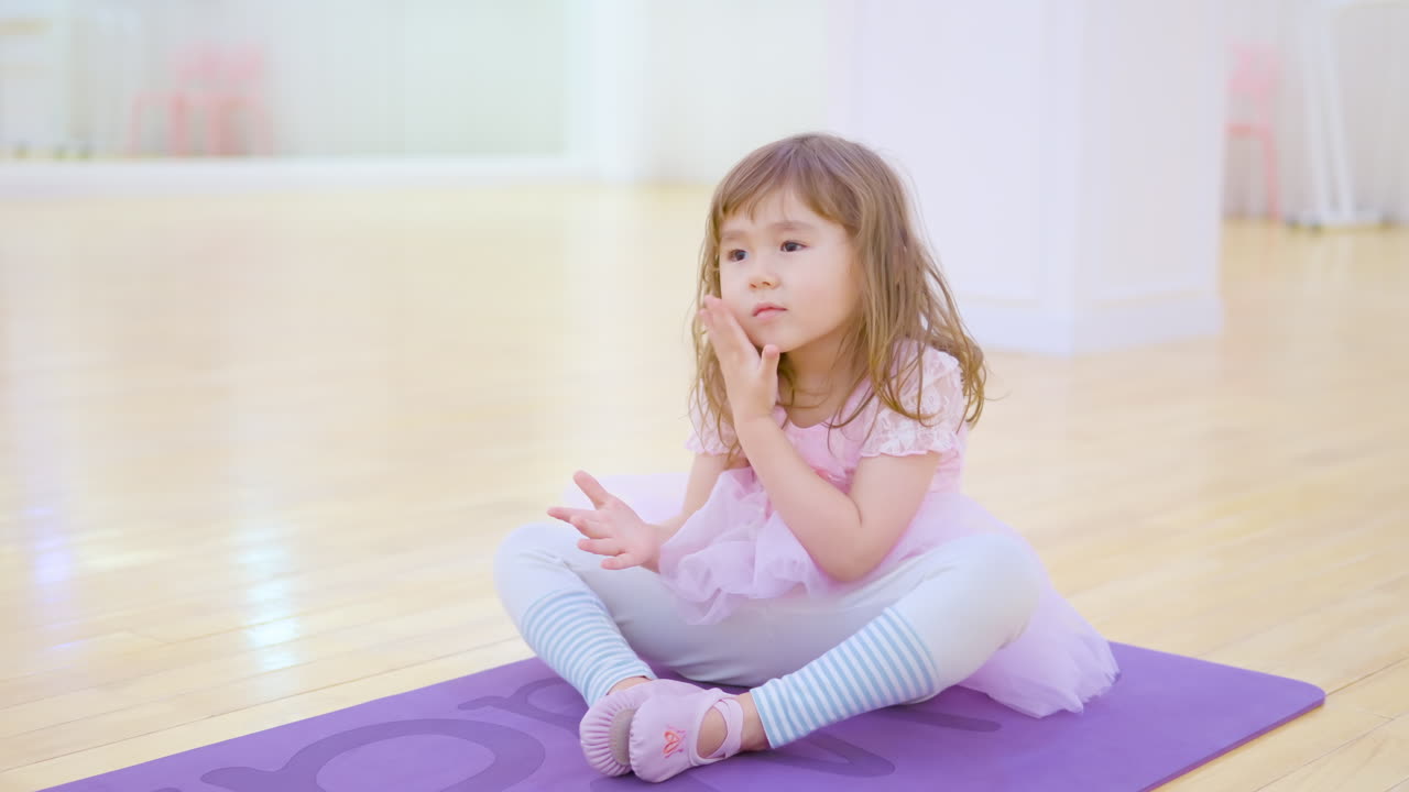Toddler Ballerina Stretches Legs in Empty Ballet Studio in Playing Style Following Teacher During Idividual Class
