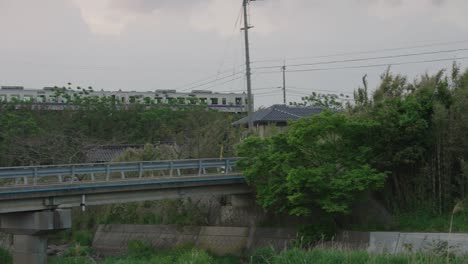 Countryside-Train-in-Japan-crossing-bridge-over-small-town