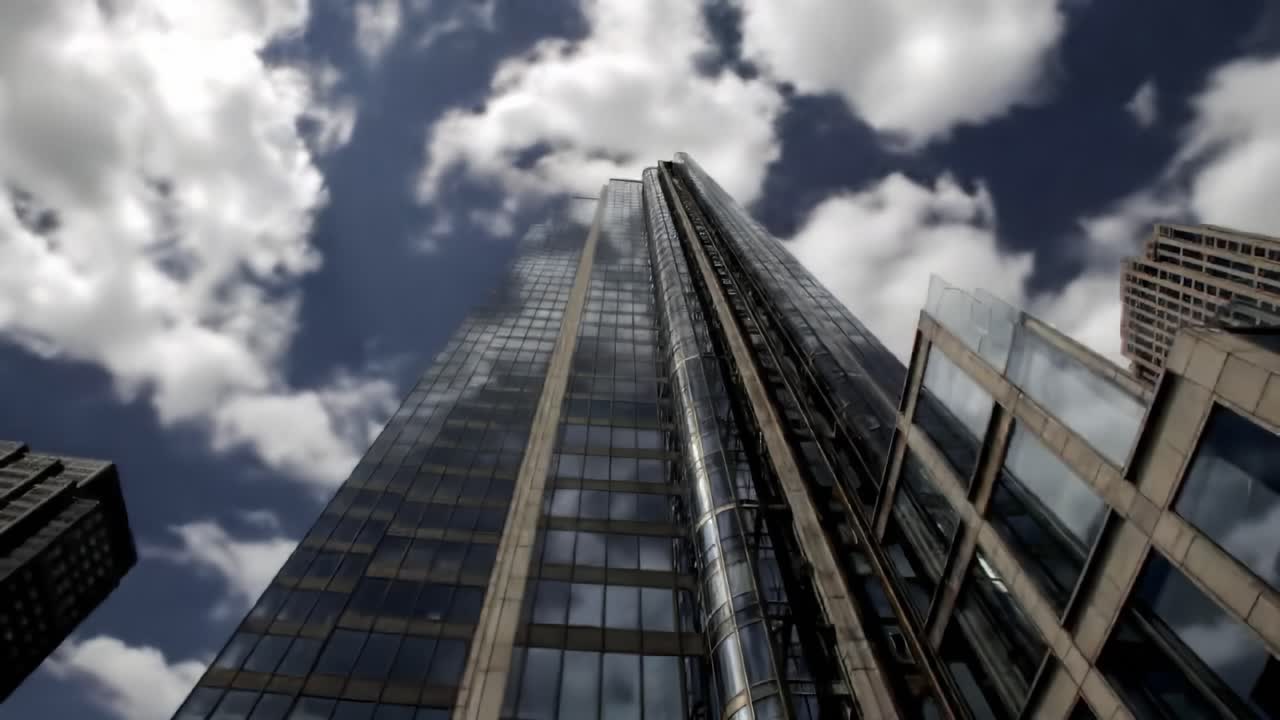 Tall glass skyscrapers reach for the clouds in a dynamic cityscape. Reflections shimmer on building surfaces, showcasing an architectural marvel against a backdrop of vibrant skies.