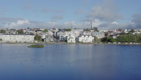 Horizonte-De-Reykjavik-Del-Centro-De-La-Ciudad-Con-La-Iglesia-Frikirkjan-En-El-Lago-Tjörnin,-Antena