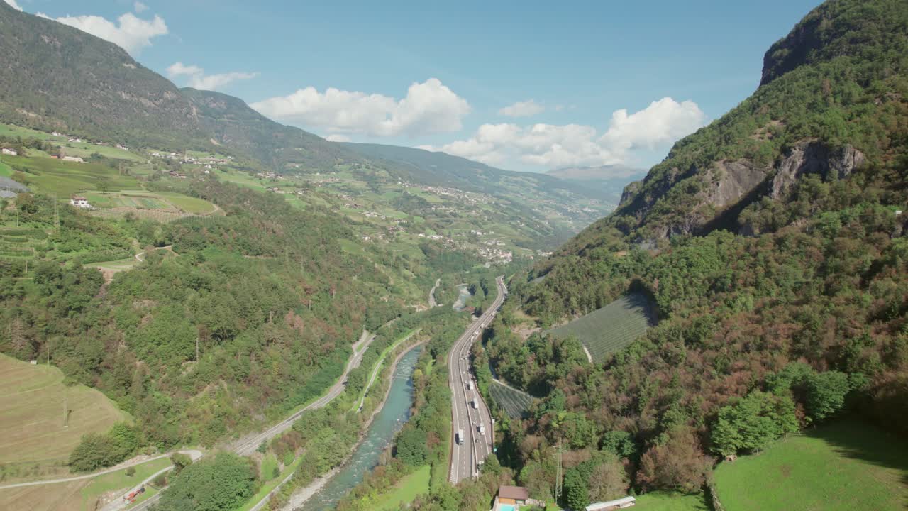 carretera que atraviesa la montaña al lado del río, coches que van al túnel, empujar en la vista del dron, tiempo soleado