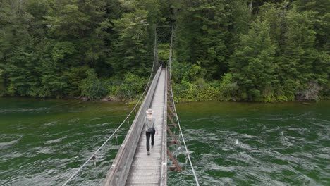 Backpacker-crossing-rainbow-bridge-in-Kepler-Track,-New-Zealand