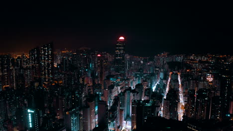drone shot, traveling to the left, of a big city during the night with a landmark business building in the middle. the streets are busy and give the shot a cyberpunk atmosphere.
