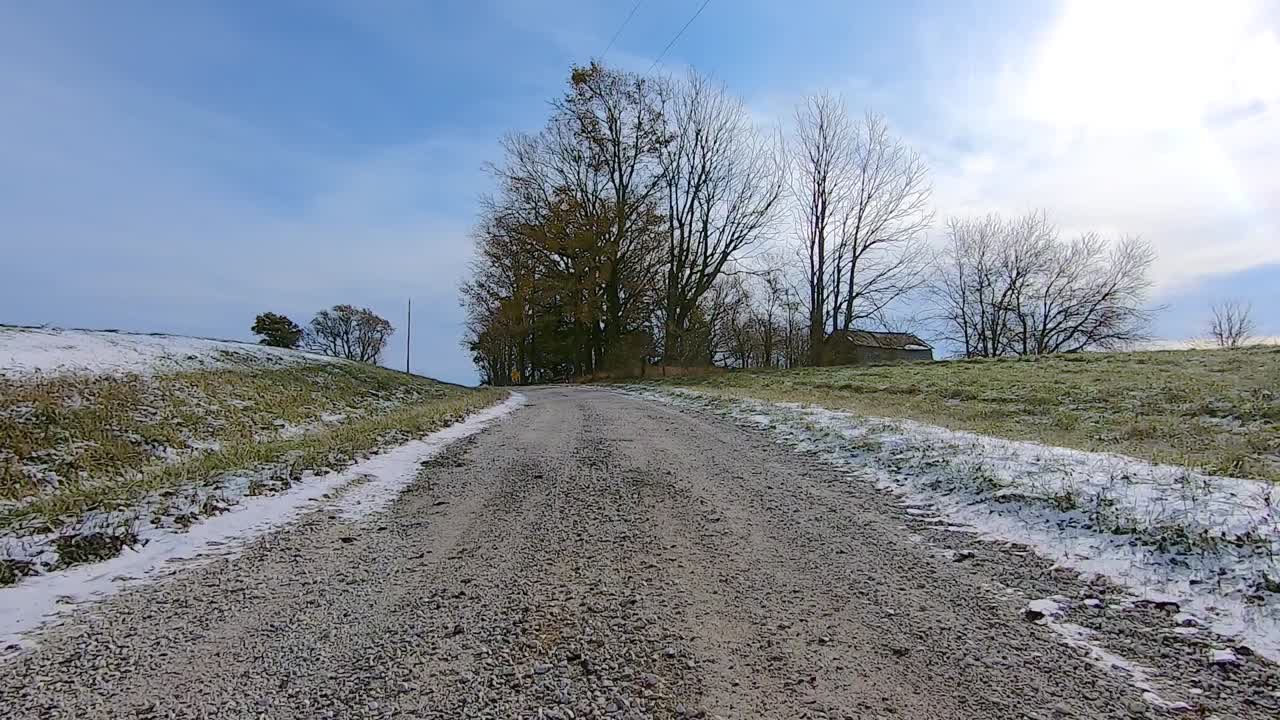 Point of View out of the drivers window; Driving past farm and field in rural Illinois USA on snow and ice.