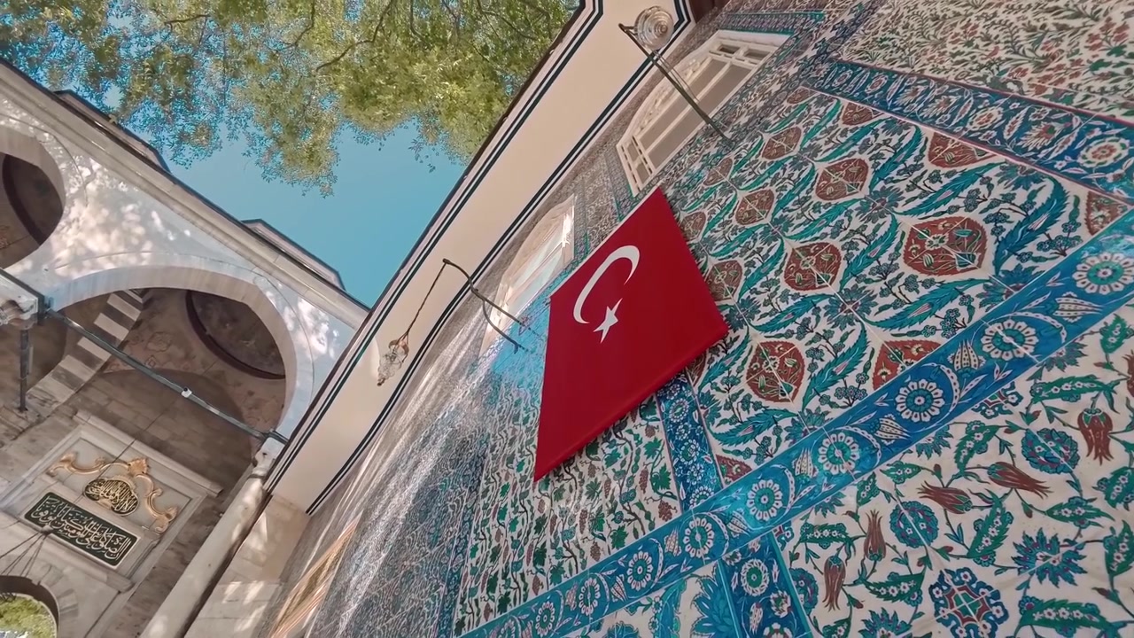Tyrkisk flag hængende på en udsmykket flisevæg i en historisk moské