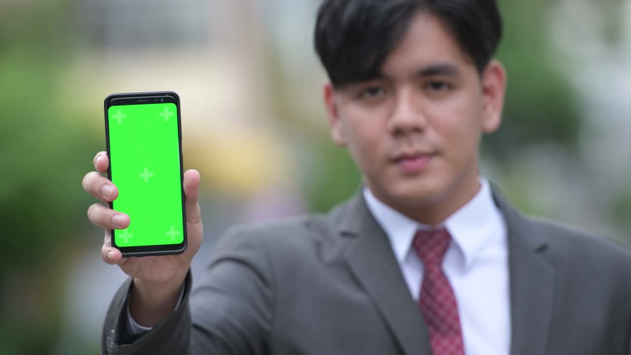 젊은 잘생긴 아시아 사업가들이 거리에서 드폰을 보여주고 있습니다.