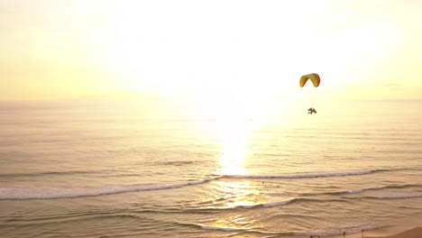 Sunset-aerial-drone-tracking-shot-of-paramotorers-over-a-beach-in-Weligama,-Sri-Lanka