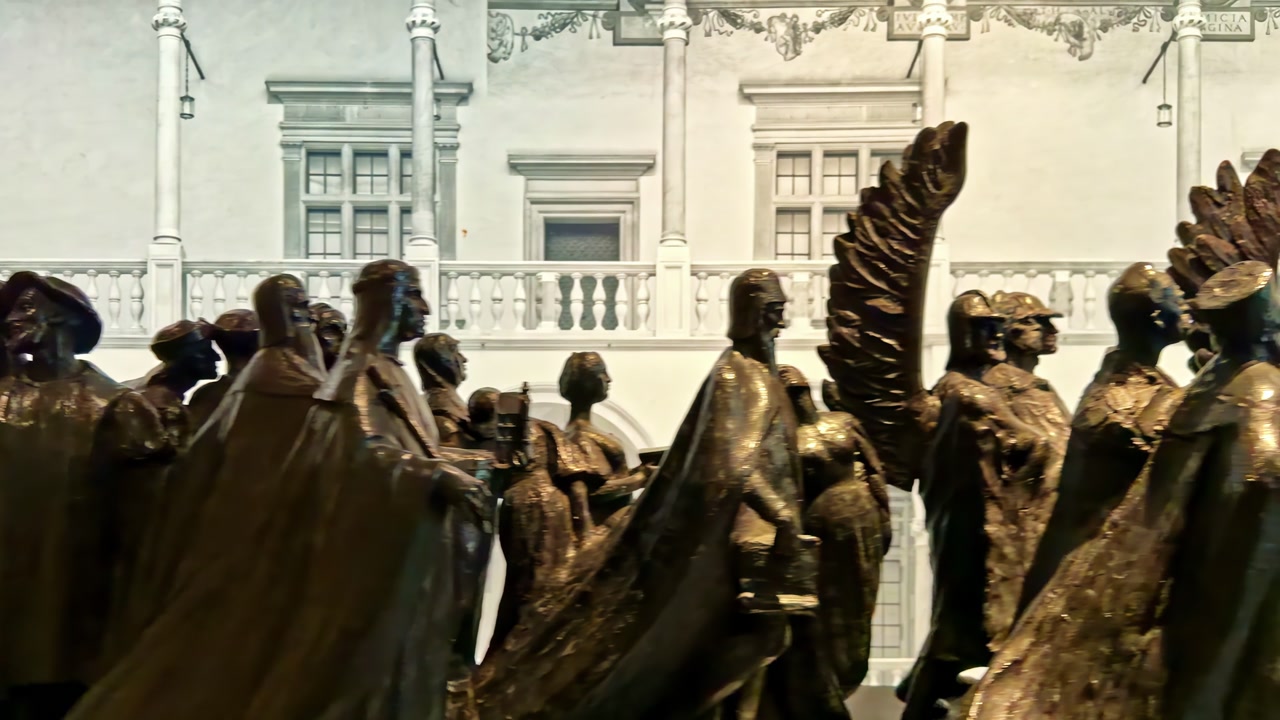 Close view of bronze statue figures in the Wawel Royal Castle courtyard, Krakow, with historic architecture in the background on an overcast day.