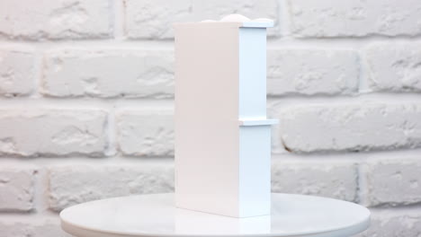 Cute white wooden cupboard rotating on the table. Little toy furniture close up at white backdrop.