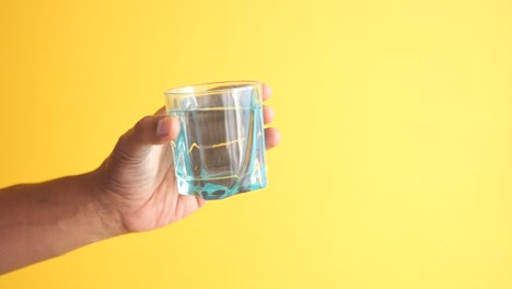 men holding a glass of water against yellow ,