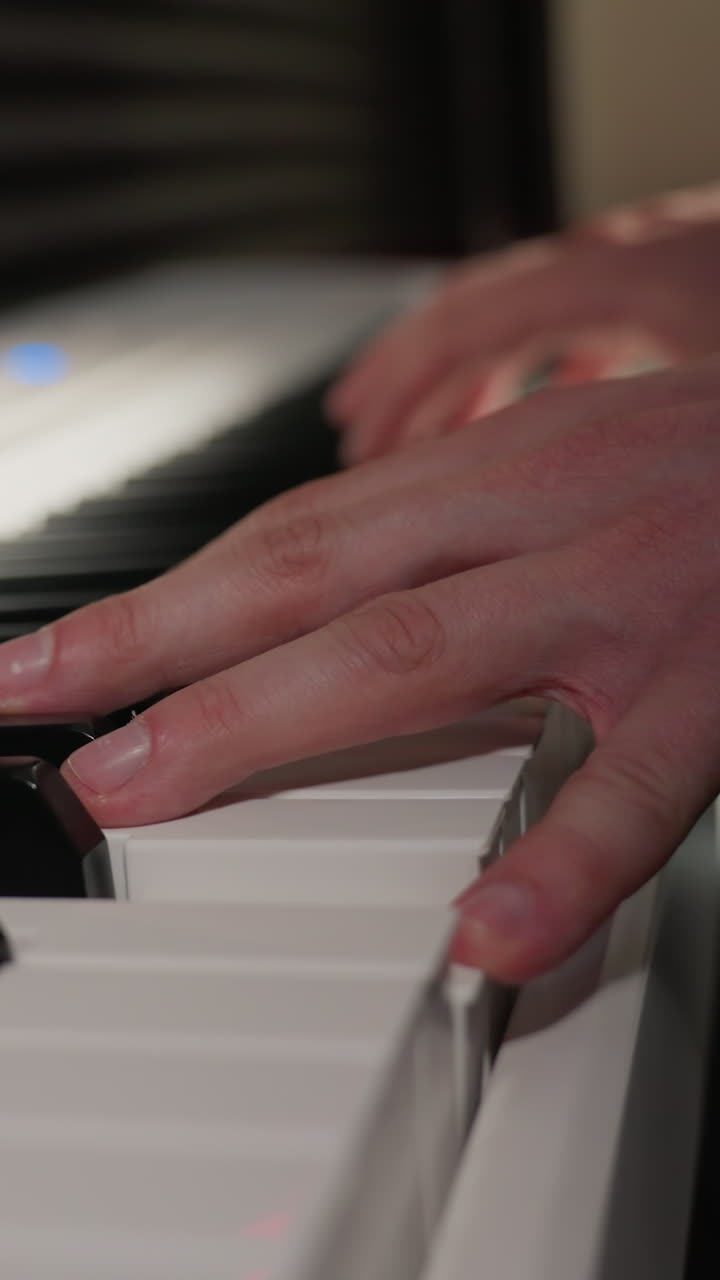 toma de primer plano de manos con camisa de manga larga tocando un piano blanco. se centra en las teclas y los dedos del piano, capturando el detalle y el movimiento de la actuación, con el fondo suavemente borroso