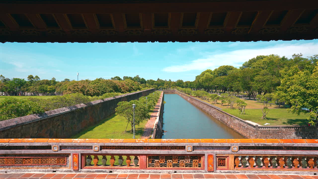 Un'inquadratura perfetta dal livello superiore della Porta di Mezzogiorno (Ngo Mon), che guarda verso il basso la linea retta del fossato di protezione, le mura in pietra e i rigogliosi giardini verdi della Cittadella