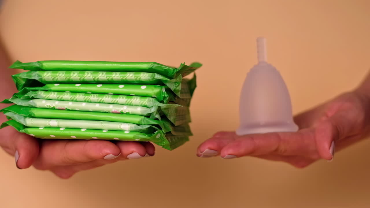 Woman hands chooses between a sanitary napkin and menstrual cup