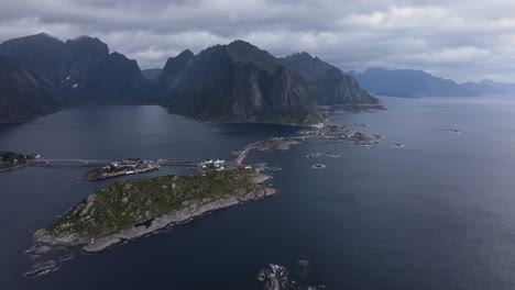 Vista-Aérea-De-Las-Islas-Sakrisoy,-Olenilsoya-Y-Hamnoy-Rodeadas-Por-El-Fiordo-Reinefjorden-Y-Escarpados-Acantilados-Montañosos-En-El-Municipio-De-Moskenes-En-El-Condado-De-Nordland-En-Noruega---Carro-Lateral