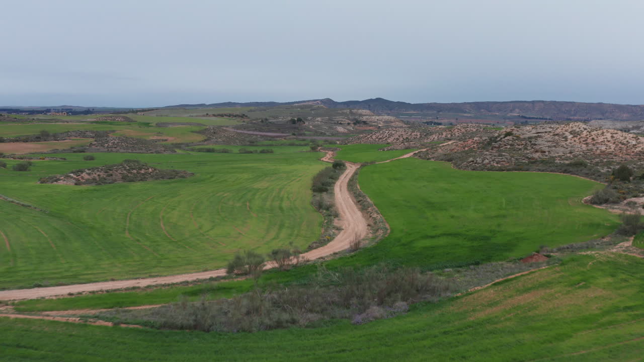 carretera de tierra tiro aéreo entre campos verdes pasto españa día nublado