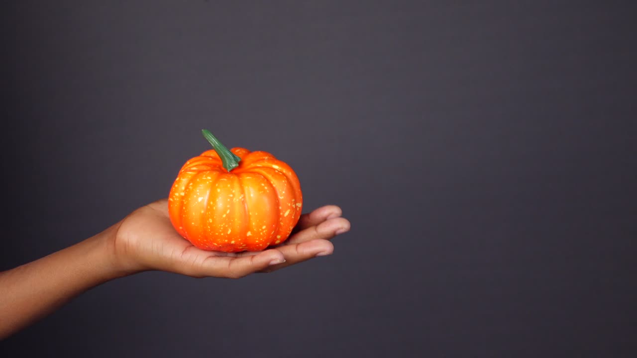 작은 오렌지색 호박을 들고 있는 손