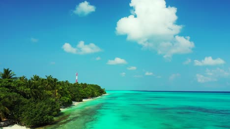 Bright-blue-sky-with-static-white-clouds-hanging-over-turquoise-lagoon-washing-shore-of-tropical-island-with-lush-vegetation-and-antenna-in-Dhigurah,-Maldives