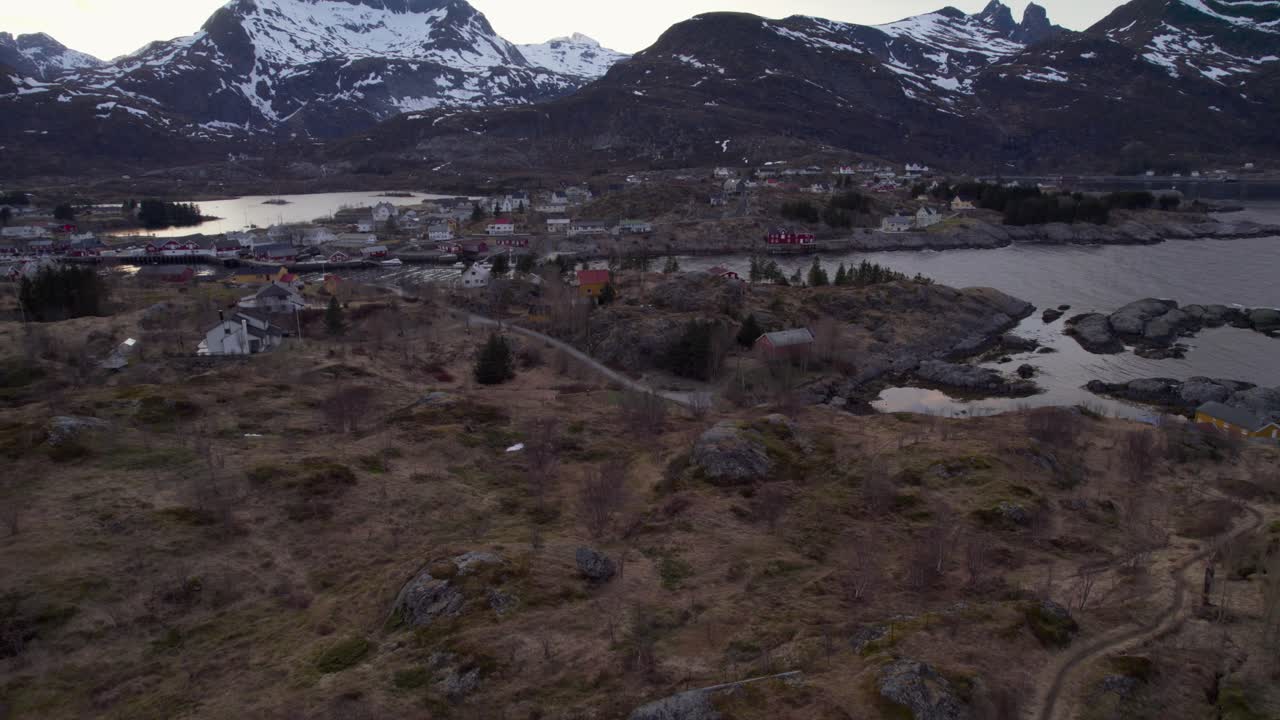 toma aérea hacia atrás de sorvagen con un faro histórico a finales del invierno en abril, isla lofoten