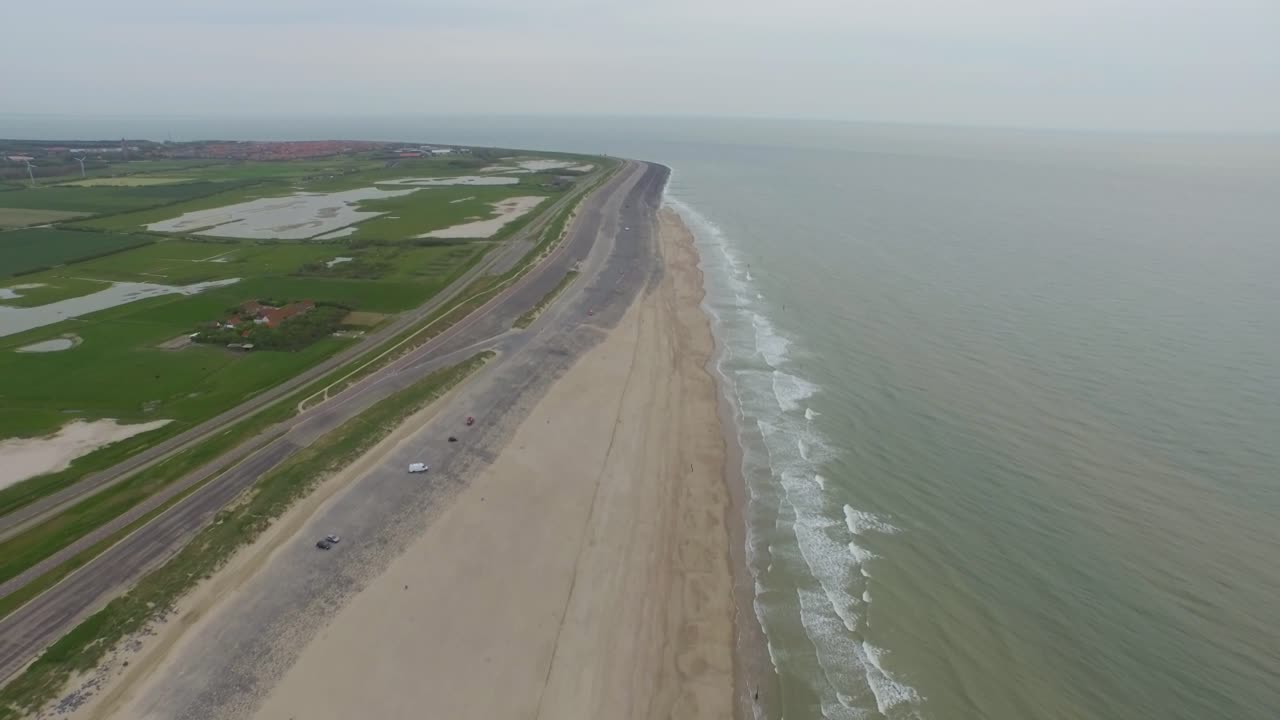 Aerial view of a coastline with beach and green fields