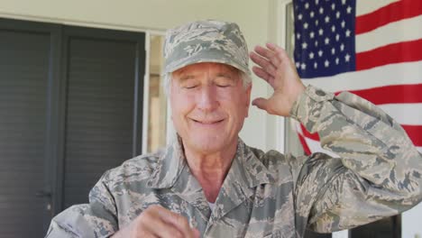 video of happy caucasian senior soldier wearing uniform standing outside house