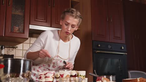 woman preparing a trifle dessert in a kitchen