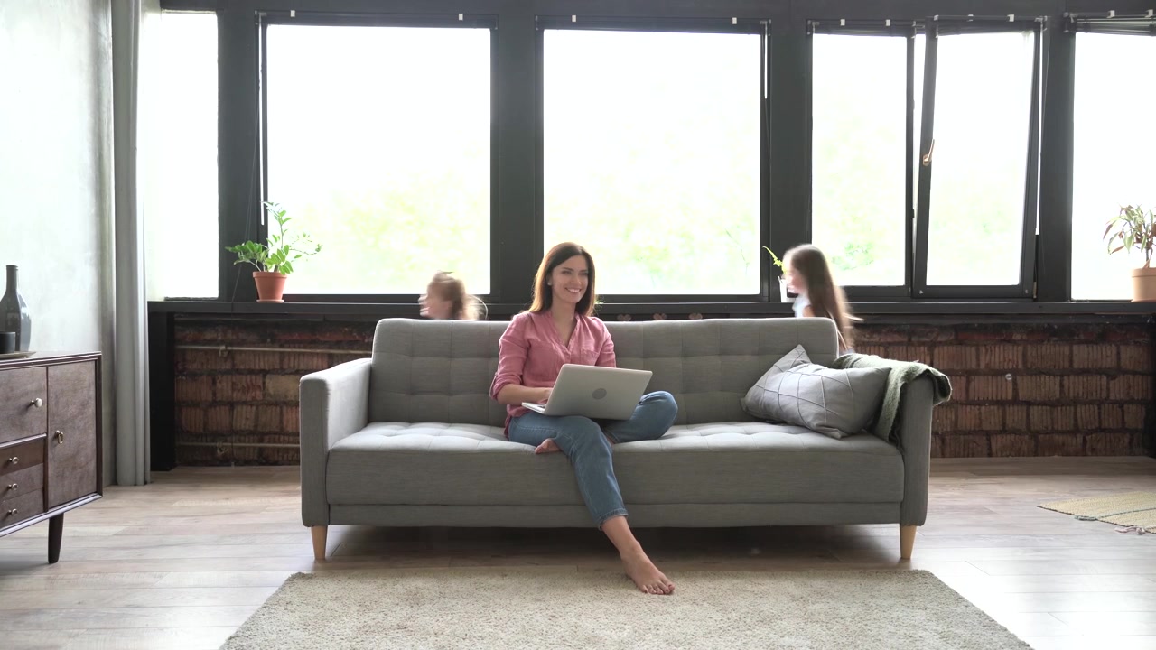 Mother Working on Laptop While Children Play in Living Room