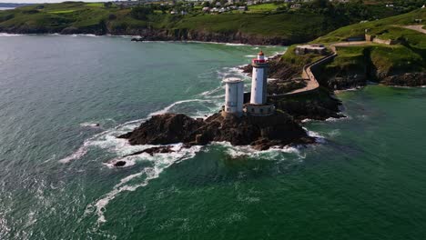 drone performs a lateral movement above the sea, revealing the petit minou lighthouse, stone path, crashing waves, cliffs and surrounding vegetation - brittany in france