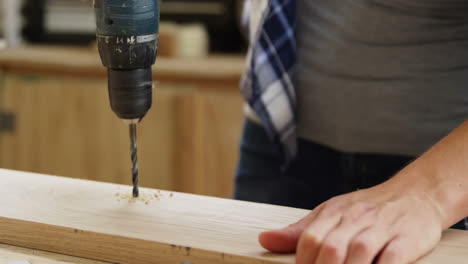 Focus-on-carpenter-drilling-a-wooden-plank