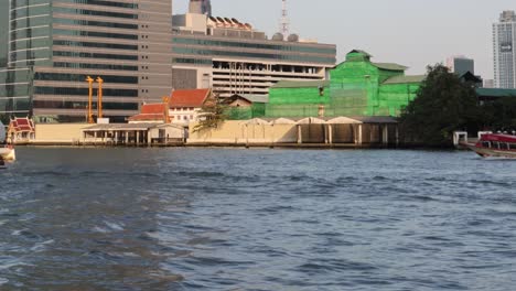 boats moving along a river near buildings