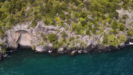 Aerial-view-of-famous-ta-moko-tattoed-face,-maori-carving-on-rocky-cliff,-Lake-Taupo,-New-Zealand