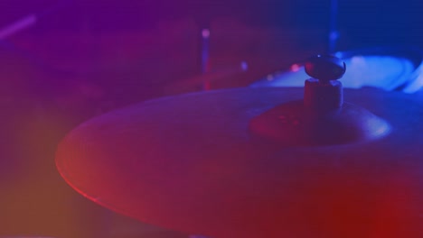 video de las manos del baterista tocando la batería, el címbal en primer plano, luz roja y azul